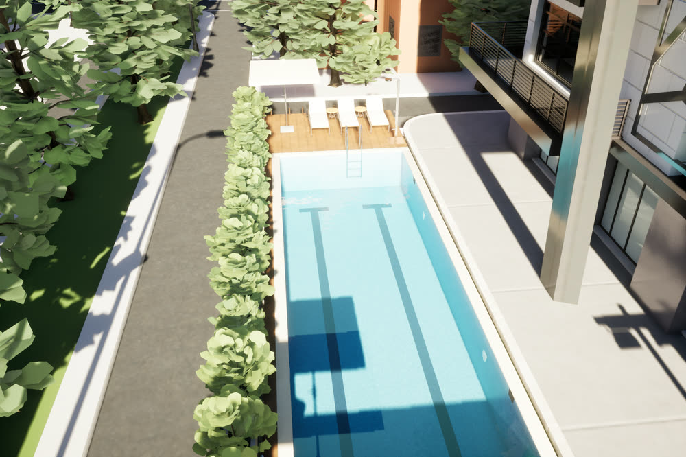 Lap pool beside the tower, with a timber deck and sun loungers at one end and a hedge and trees along its side.